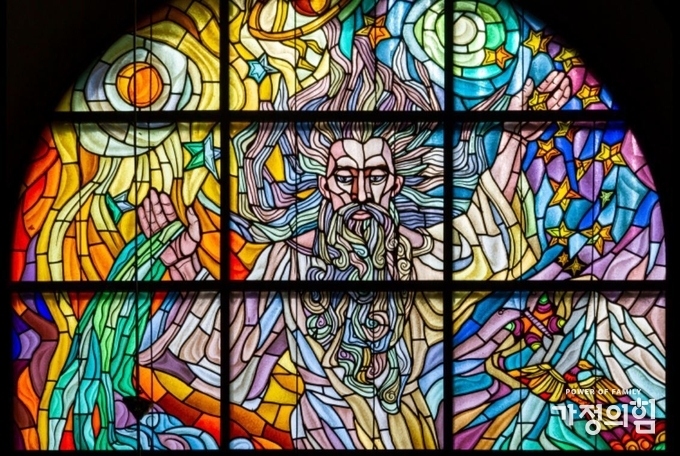A stained-glass window depicting the Creation of the World with the words "And God said, Let us make..." Roman Catholic Church of Saint Anne.